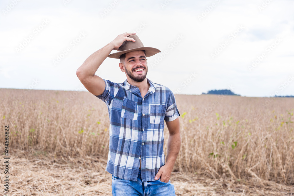 Portrait of young Latin farmer man in the casual shirt in the farm on the farm background.