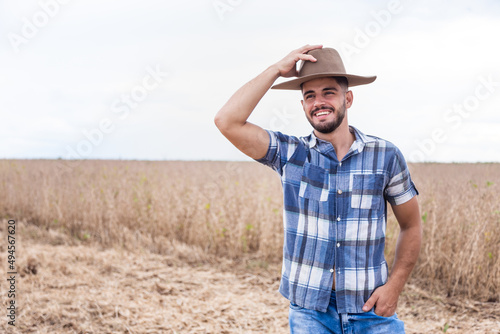 Portrait of young Latin farmer man in the casual shirt in the farm on the farm background.