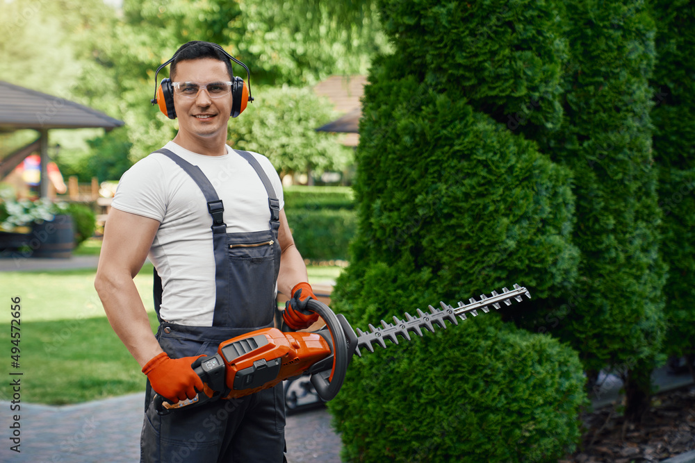 Smiling caucasian man in overalls, safety glasses and gloves holding