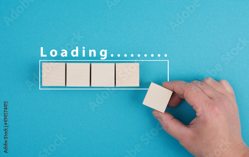 The word loading is standing over the progress bar, hand puts last cube to the row, business, education and marketing concept download a new program