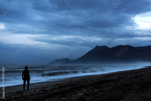 Silhouette of a man on the shores of the Mediterranean Sea  against the backdrop of mountains  at night  sea  mountains  man  night.