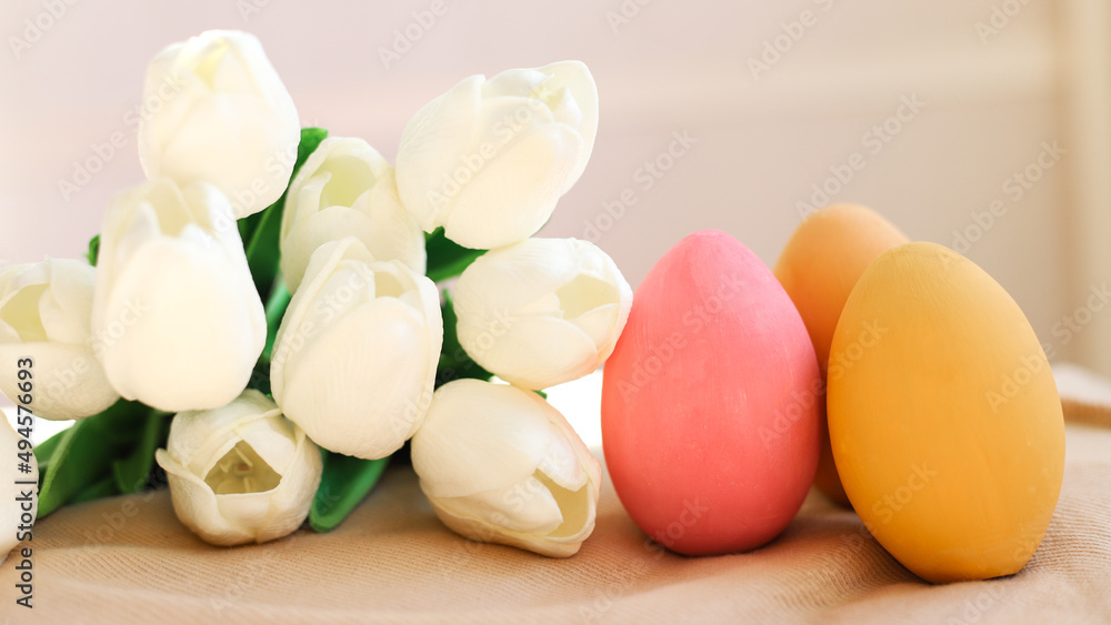 Three colored Easter eggs close-up and white tulips side by side. The concept of holidays and Easter Three colored Easter eggs close-up and white tulips side by side. The concept of holidays and Easter