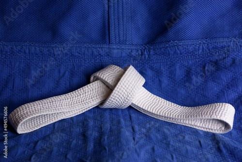 White judo, aikido or karate belt on blue budo gi. Concept is applicable to sports, business or education photo