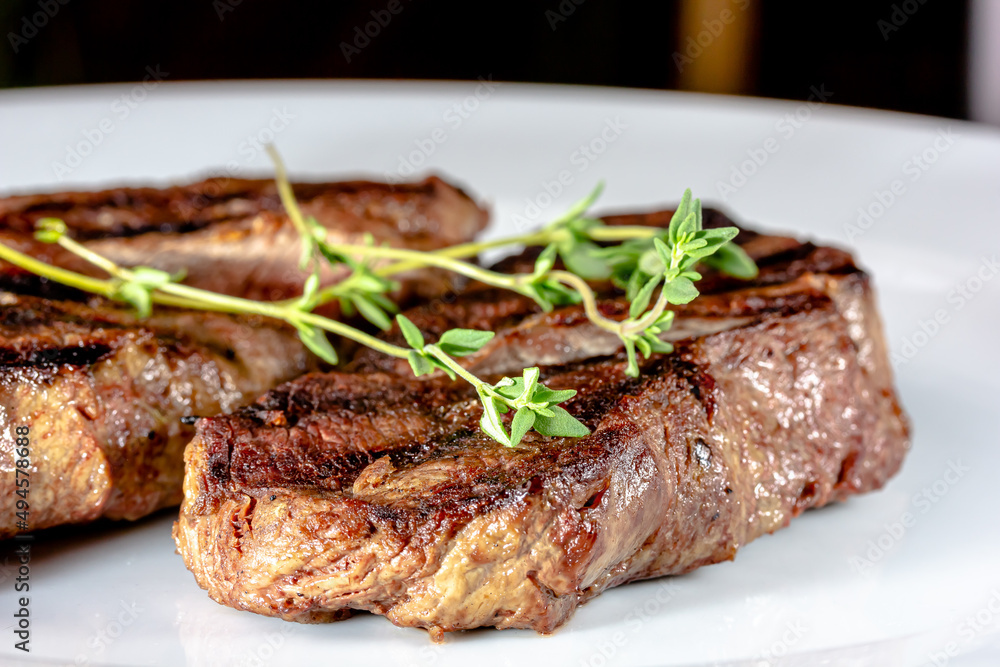 Grilled marbled beef steak lies on a white plate Grilled marbled beef steak lies on a white plate