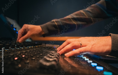 Manos mezclando en una mesa de mezclas. Anillo indica compromiso con su trabajo.