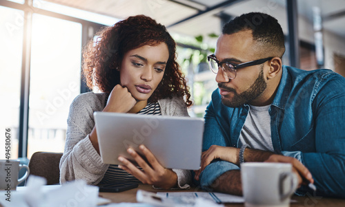 Searching for an insurance policy that suits their needs. Shot of a young couple using a digital tablet while planning their budget together at home.