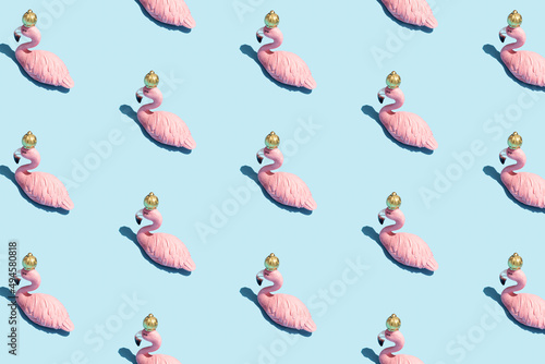 Trendy sunlight Summer pattern made with pink flamingo toy on bright light blue background. Minimal summer concept.