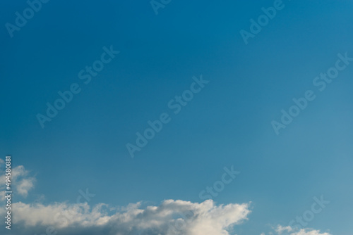 bright blue summer sky with a strip of white clouds at the bottom edge of the picture 