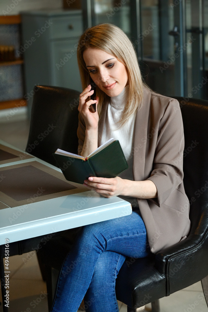 business confident beautiful woman sits at a table in a cafe waiting for an order and decides her working moments on the phone business confident beautiful woman sits at a table in a cafe waiting for an order and decides her working moments on the phone