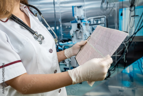 female hand holding and examines the cardiogram of the patient in operating room