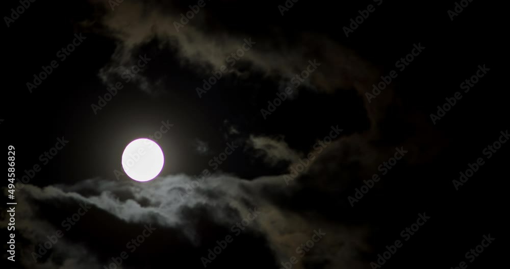 A full moon moves across the dark clouds sky A full moon moves across the dark clouds sky