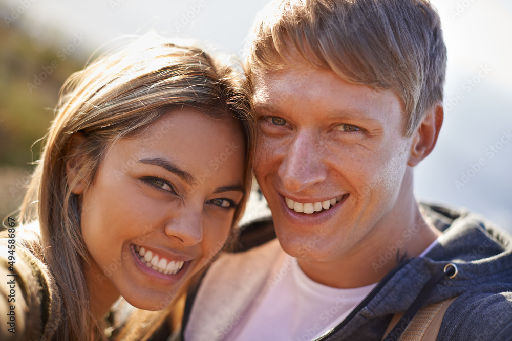 They love getting outdoors together. Portrait of an affectionate young couple standing outside together in the sun. They love getting outdoors together. Portrait of an affectionate young couple standing outside together in the sun.