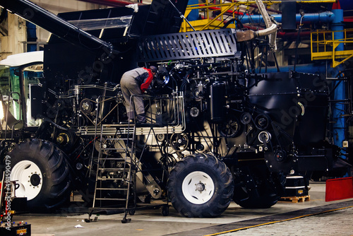 Industrial workers assembles agricultural harvester in workshop