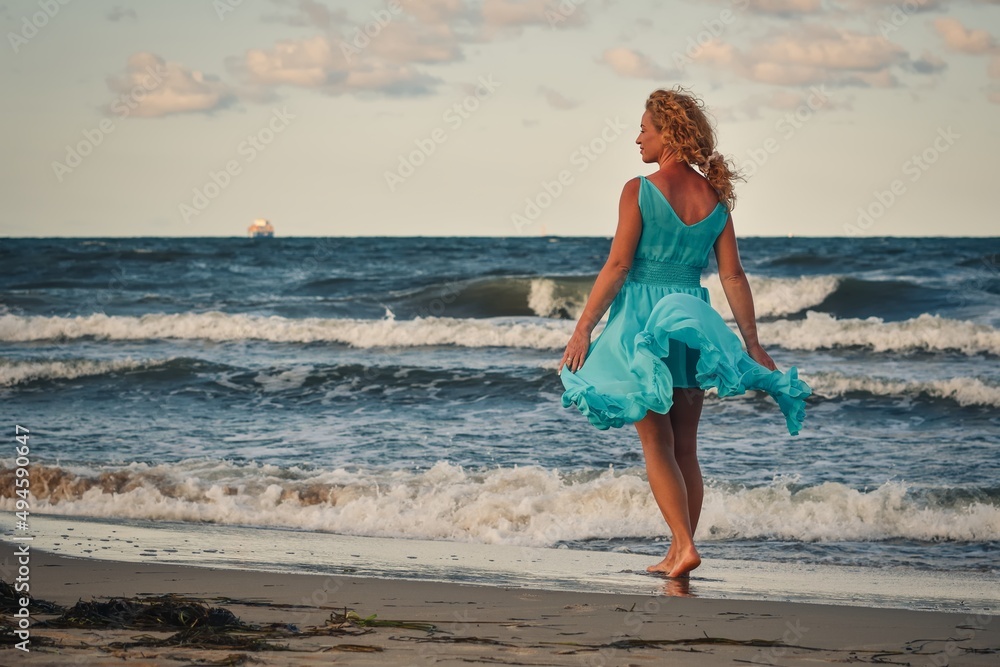 Beautiful blonde haired woman on the beach. Girl in a blue dress at the Polish seaside. Beautiful blonde haired woman on the beach. Girl in a blue dress at the Polish seaside.