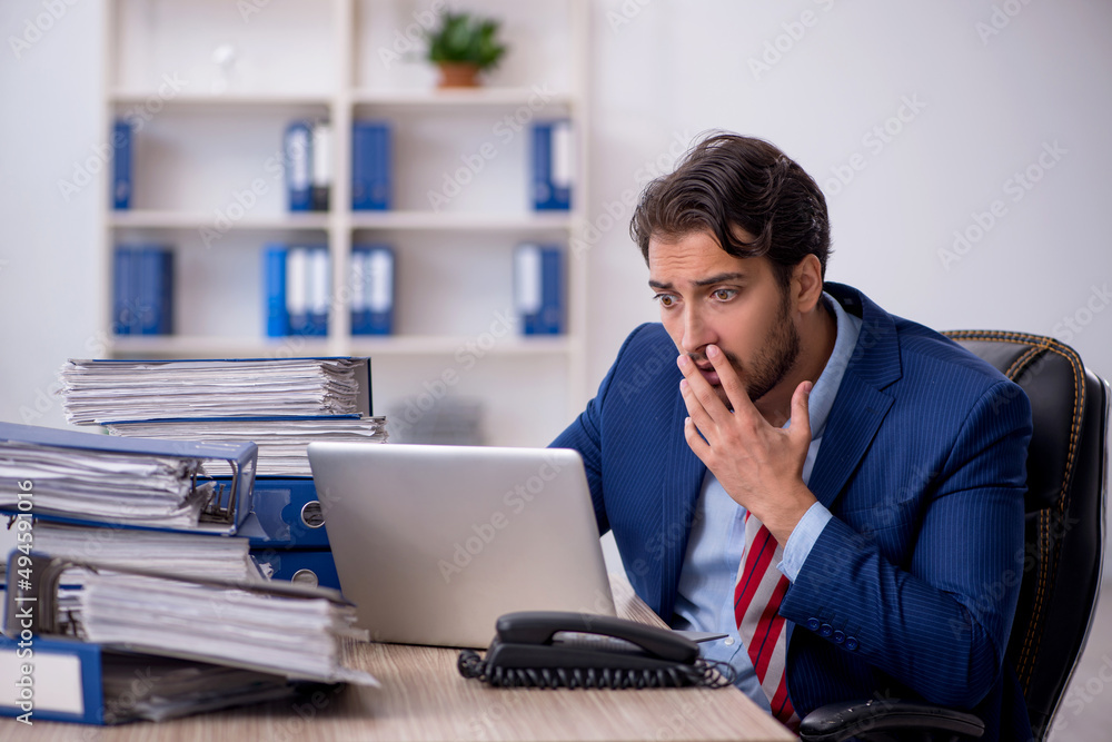 Young male employee and too much work in the office Young male employee and too much work in the office
