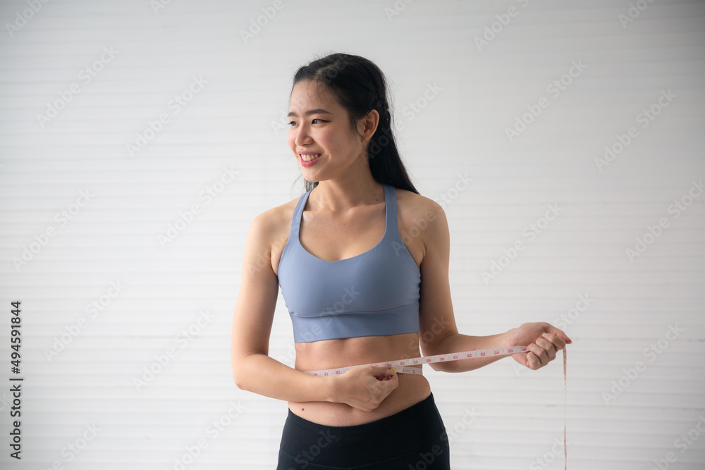 young Asian woman measure a body proportions, health fitness to slim body and diet concept, female person using tape with her body care to checking a shape size