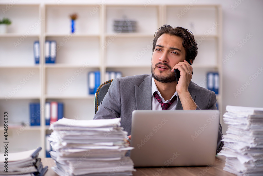 Obraz premium Young male employee and too much work in the office