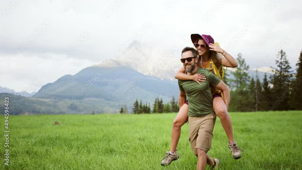 Young man giving piggyback ride to woman while hiking through mountains. Young man giving piggyback ride to woman while hiking through mountains.