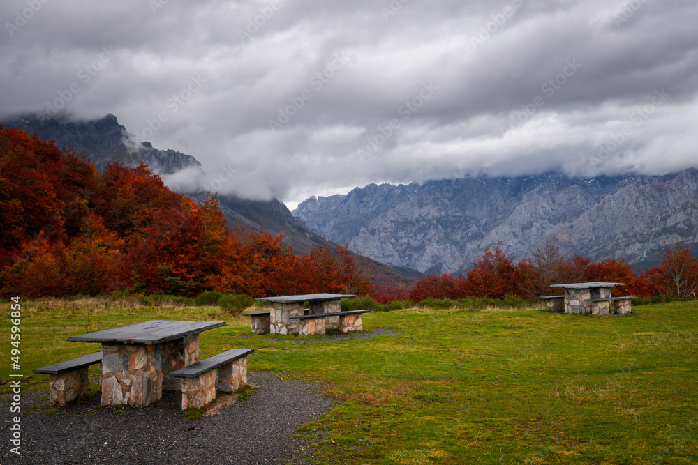 Puerto de Panderrueda viewpoint with picnic tables on a colorful autumn mountain range landscape on a cloudy day, Spain