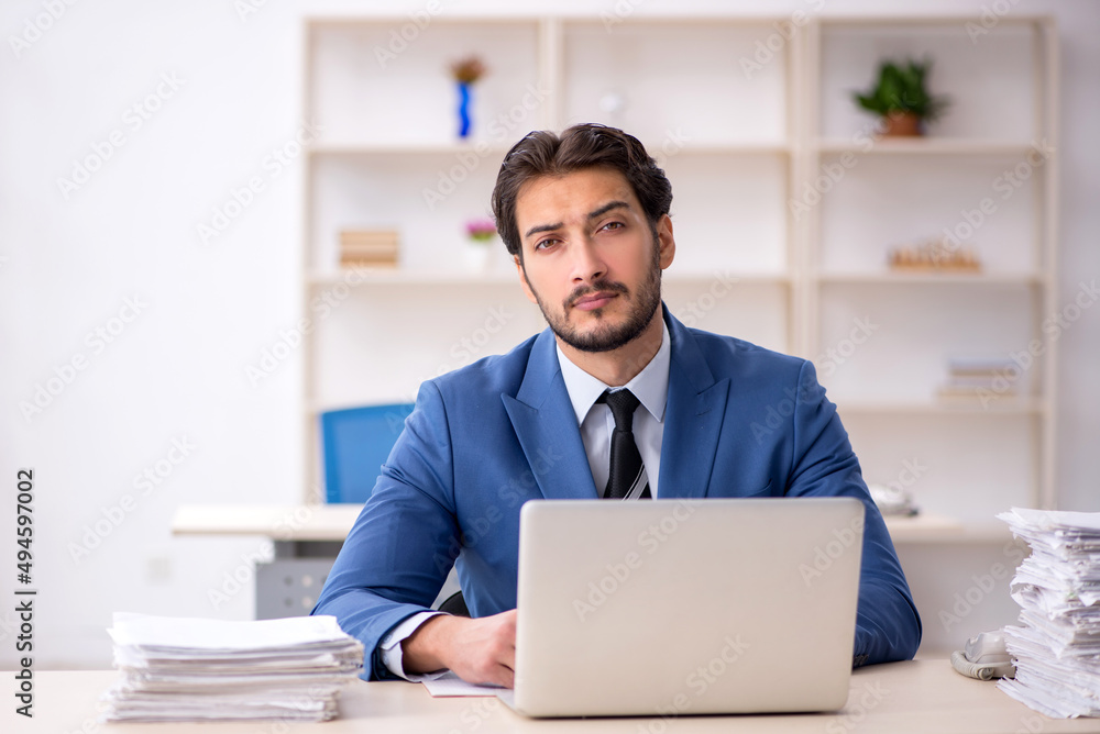 Young male employee and too much work in the office Young male employee and too much work in the office