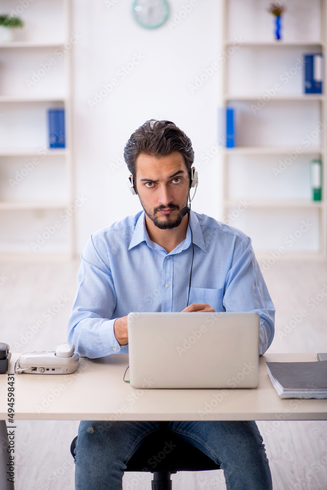 Young male call center operator working at his desk Young male call center operator working at his desk