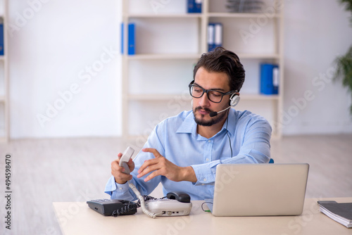 Young male call center operator working at his desk