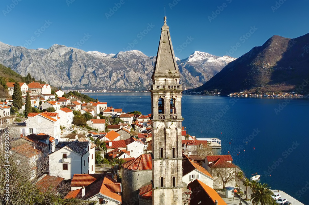Breathtaking panoramic aerial drone view of ancient city of Perast, Montenegro. Old medieval little town with red roofs and with majestic mountains on background. Church of st. Nickolas