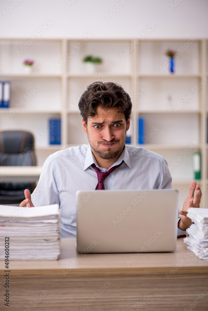 Young male employee and too much work in the office Young male employee and too much work in the office