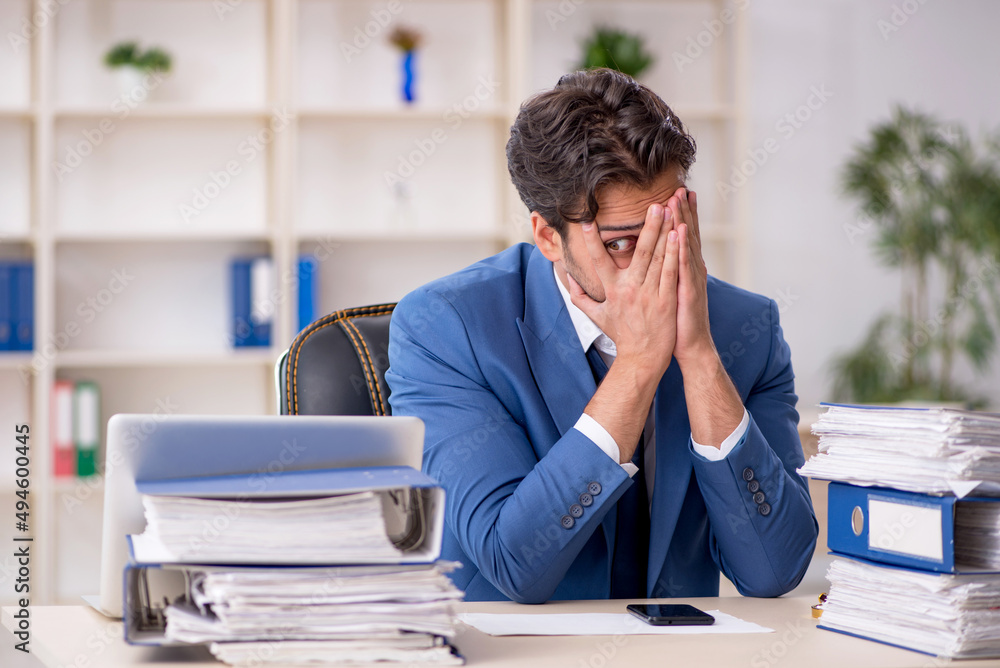 Young male employee and too much work in the office Young male employee and too much work in the office