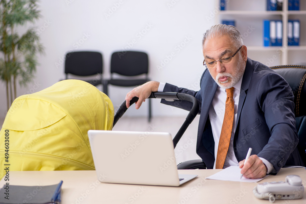 Old male employee looking after new born at workplace Old male employee looking after new born at workplace