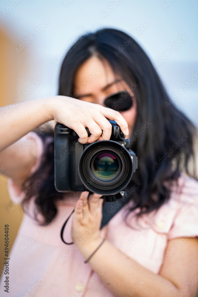 Amateur sunglasses Asian Woman take a photo with professional mirrorless camera at outdoor blue rooftop building in twilight time. Amateur sunglasses Asian Woman take a photo with professional mirrorless camera at outdoor blue rooftop building in twilight time.