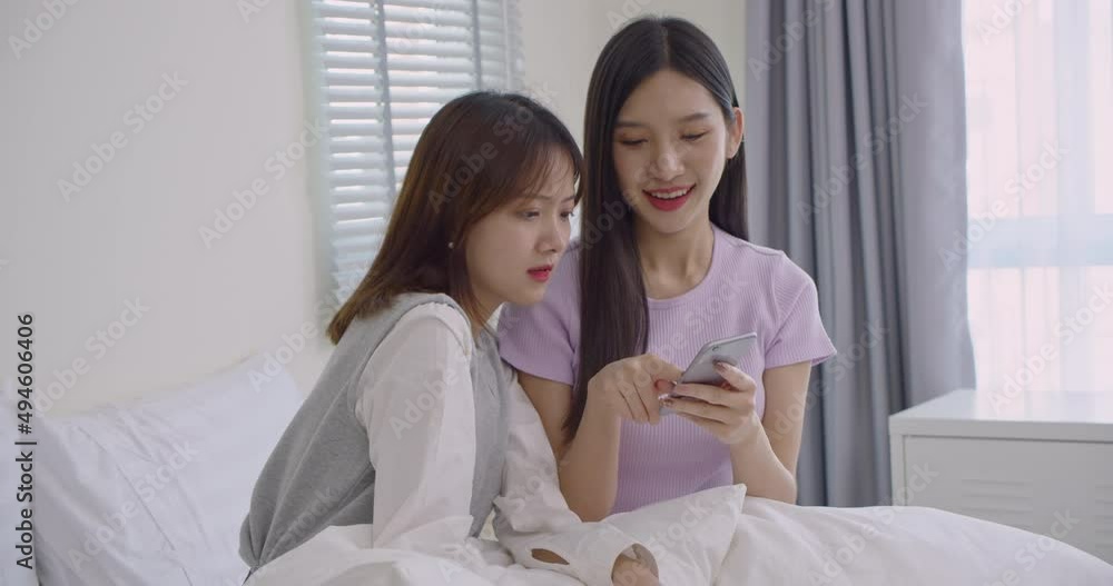 Pretty Asian young are having fun on social media on the bed.Two teenage girls rejoice when they see a text message on their cell phone.Lifestyle concept. Pretty Asian young are having fun on social media on the bed.Two teenage girls rejoice when they see a text message on their cell phone.Lifestyle concept.