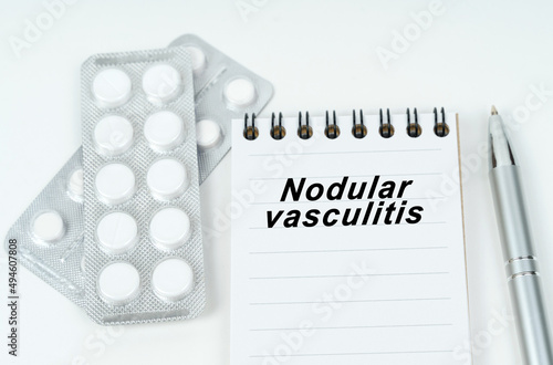 On a brown surface lie pills, a pen, a stethoscope and a notebook with the inscription - Nodular vasculitis photo