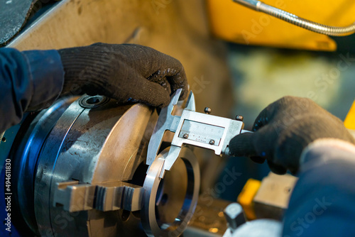 man in black gloves measuring the lathe with a device