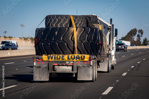 Heavy equipment tires being hauled on a flatbed trailer with a wide load sign photo