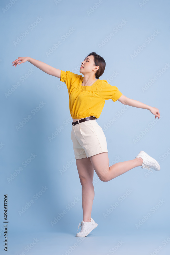 Full length image of young Asian woman posing on blue background Full length image of young Asian woman posing on blue background
