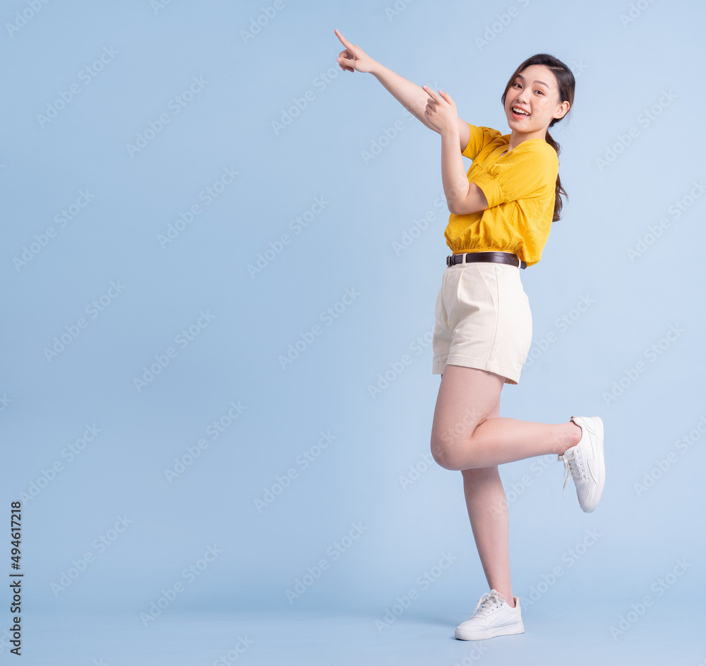 Full length image of young Asian woman posing on blue background Full length image of young Asian woman posing on blue background