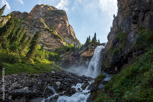 Beautiful waterfall in mountains with. Barskoon waterfall - splashes of Champaign. Travel, tourism in Kyrgyzstan concept.