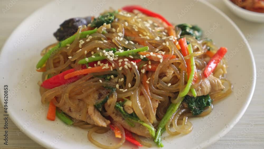 japchae or stir-fried Korean vermicelli noodles with vegetables and pork topped with white sesame - Korean traditional food style japchae or stir-fried Korean vermicelli noodles with vegetables and pork topped with white sesame - Korean traditional food style