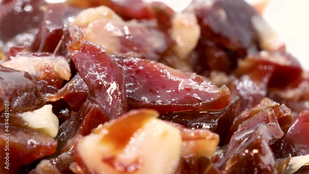 Spanish serrano ham pieces rotating on white surface, macro shot. Close view of spanish prosciutto in 4k. Spanish serrano ham pieces rotating on white surface, macro shot. Close view of spanish prosciutto in 4k.