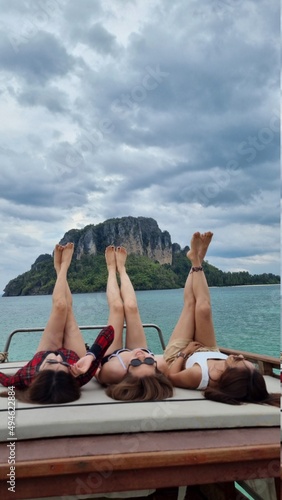 Tree women lay on the boat and put the legs up to the sky in summer vacation with swimsuits.