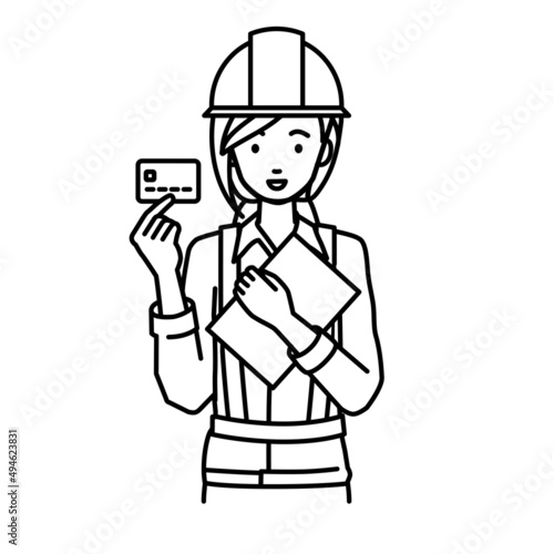 立って書類とカードを手に持つ工事現場の女性