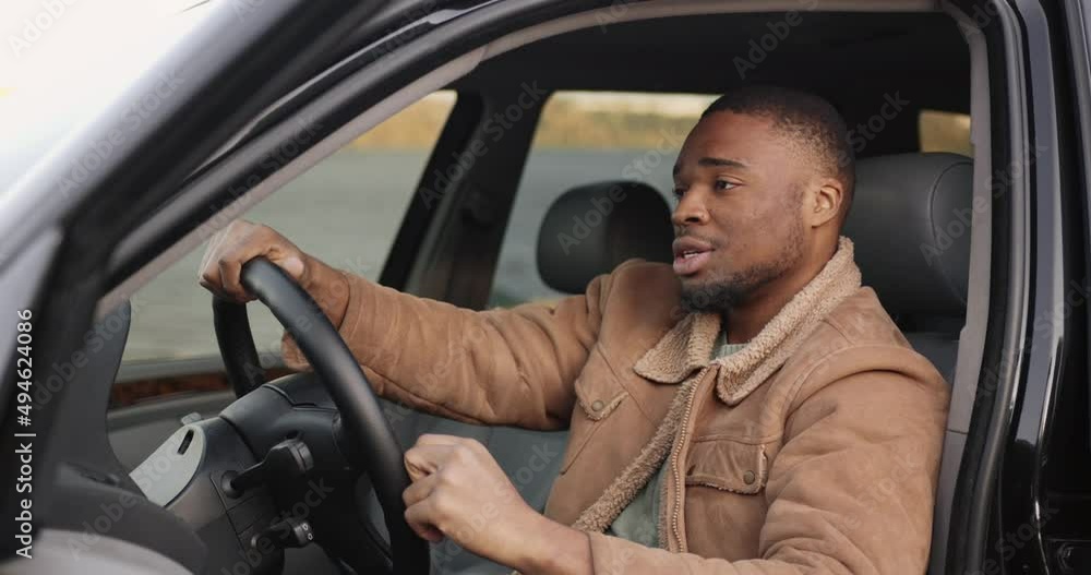 Fruestrated black driver behind the wheel in a black car Fruestrated black driver behind the wheel in a black car