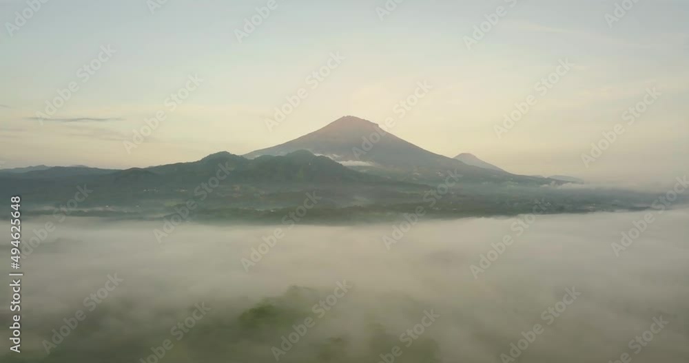 Mystic Aerial forward flight over tropical landscape covered with fog during sunny and cloudy day - Massive Mount Sumbing in background Mystic Aerial forward flight over tropical landscape covered with fog during sunny and cloudy day - Massive Mount Sumbing in background