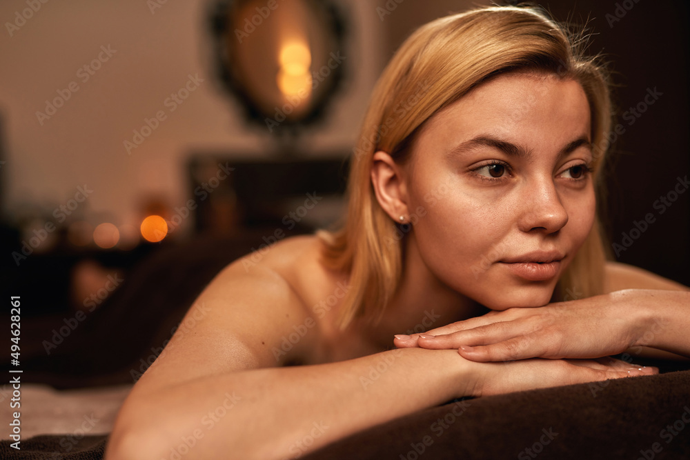 Thoughtful woman resting on massage table in spa Thoughtful woman resting on massage table in spa