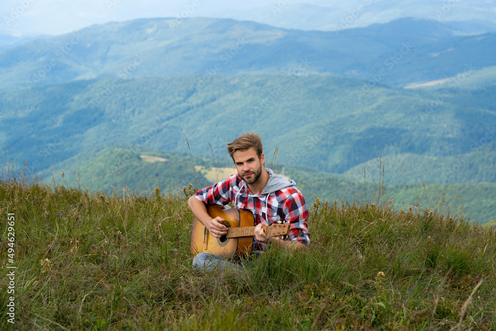 Music outdoors. Sexy man with guitar in checkered shirt, hipster camping and hiking. Man with bare muscular torsowith guitar. Country music song. Music outdoors. Sexy man with guitar in checkered shirt, hipster camping and hiking. Man with bare muscular torsowith guitar. Country music song.
