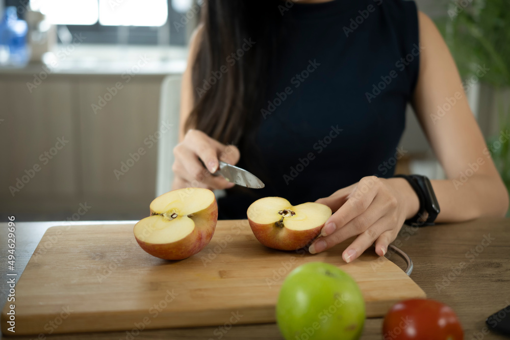 Woman holding knife and cutting apple on wooden cutting board during preparing healthy food. Woman holding knife and cutting apple on wooden cutting board during preparing healthy food.