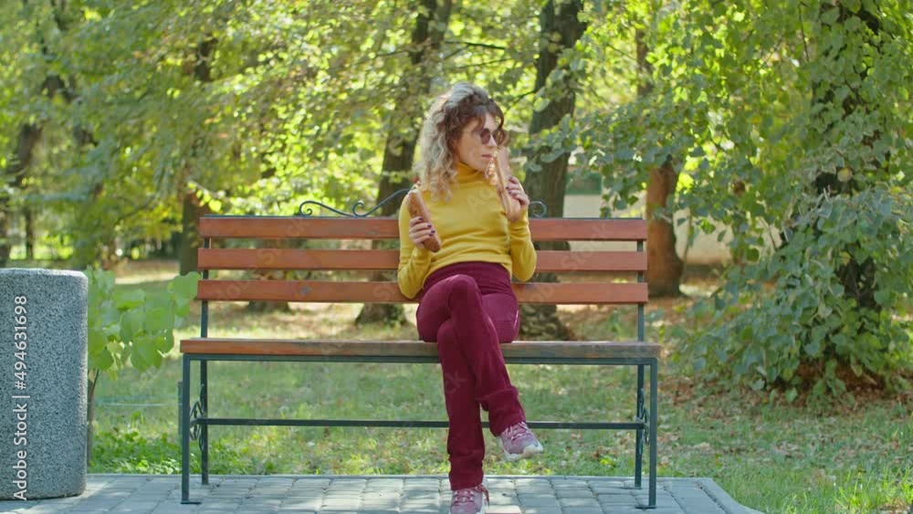 young happy woman eating baguette in city park. girls have fun together. youth, serenity, summer or autumn park. young happy woman eating baguette in city park. girls have fun together. youth, serenity, summer or autumn park.