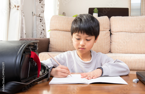 学校から帰宅してリビングで宿題をする日本人の男の子 photo