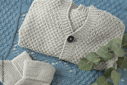 warm knitted baby cardigan and cute baby socks. A set of clothes and accessories for newborns. Flat lay, top view. hand knitted background